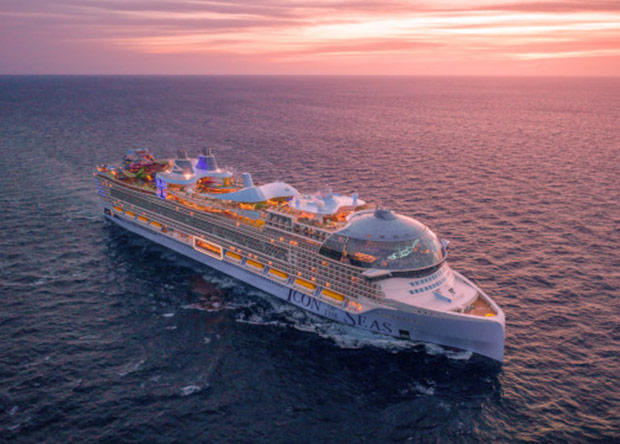 Lyxkryssaren Icon of the Seas seglar över öppet hav i solnedgången, med upplysta däck och imponerande moderna faciliteter.