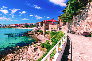 Kustpromenad i Sozopol, Bulgarien med stenmur, klippor och turkost hav.