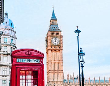 Röd telefonkiosk framför Big Ben i London under en klar himmel.