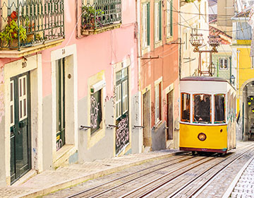 Gul spårvagn på en brant gata med färgglada hus i Lissabon.