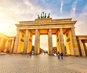 Berlins Brandenburger Tor i solnedgång, med gående och cyklister i förgrunden.