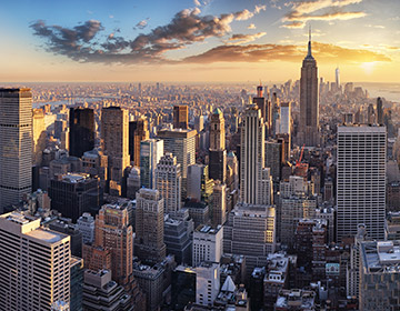 Solnedgång över New Yorks skyline med skyskrapor och Empire State Building.