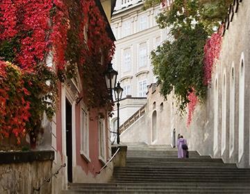 Romantisk trappa i höstligt Prag med färgglada löv, lyktor och klassisk arkitektur.